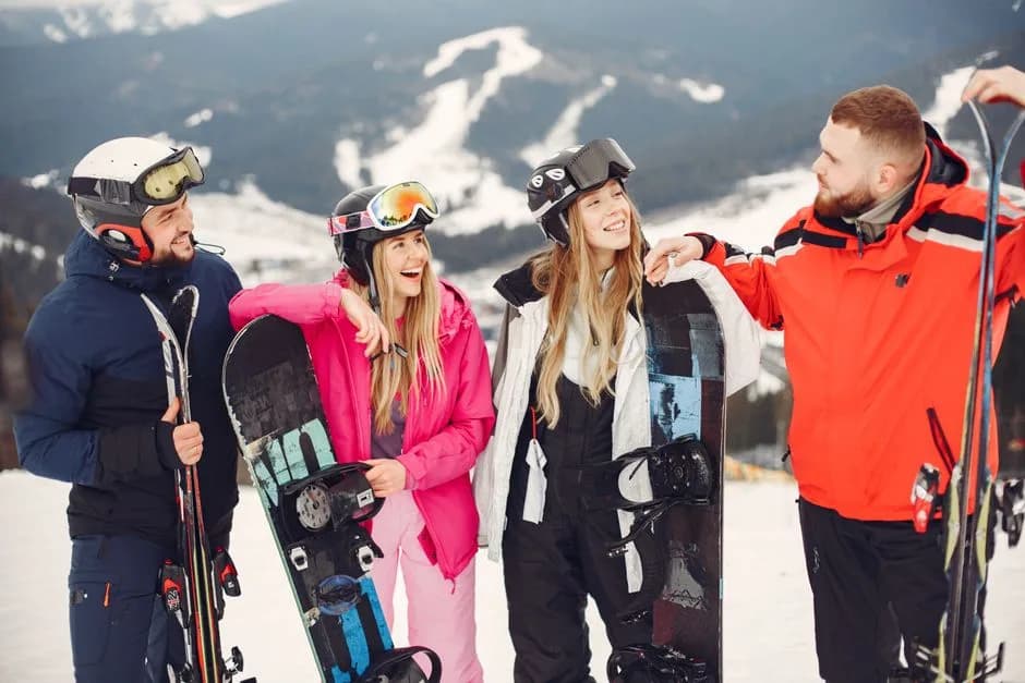 Un grupo de amigos con esquís y ropa de nieve en lo alto de una pista