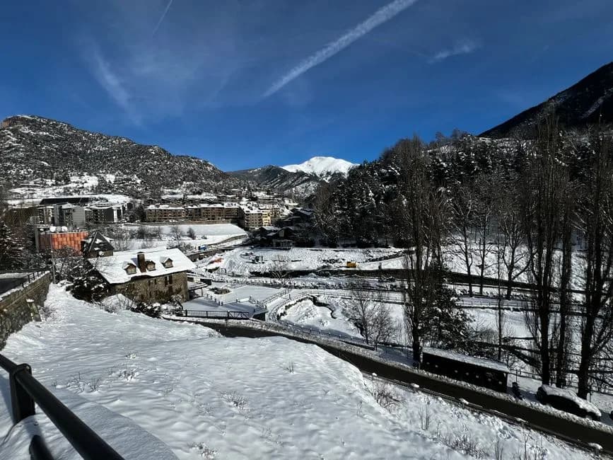 Pueblo de montaña con casas de piedra y tejados nevados al pie de laderas blancas