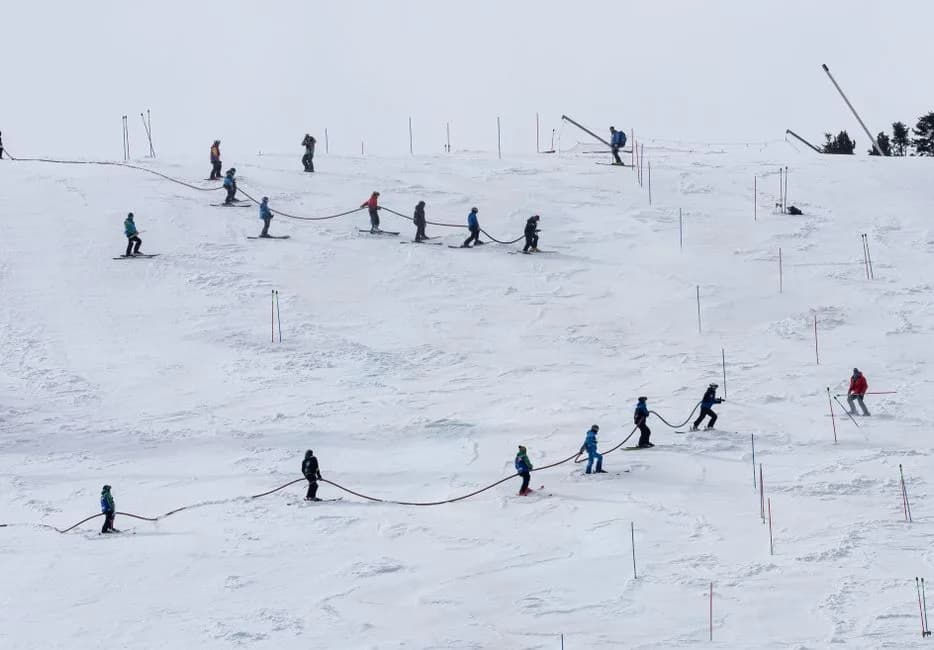 Pista de esquí del Pirineo con nieve al principio de la temporada y esquiadores bajando