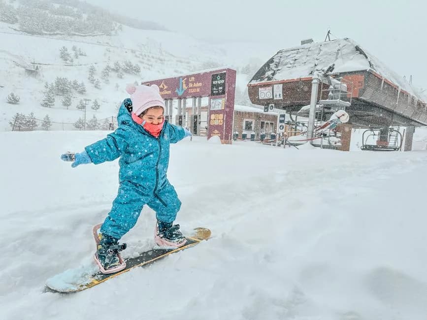 Un esquiador y un snowboarder principiantes bajando juntos por una pista suave