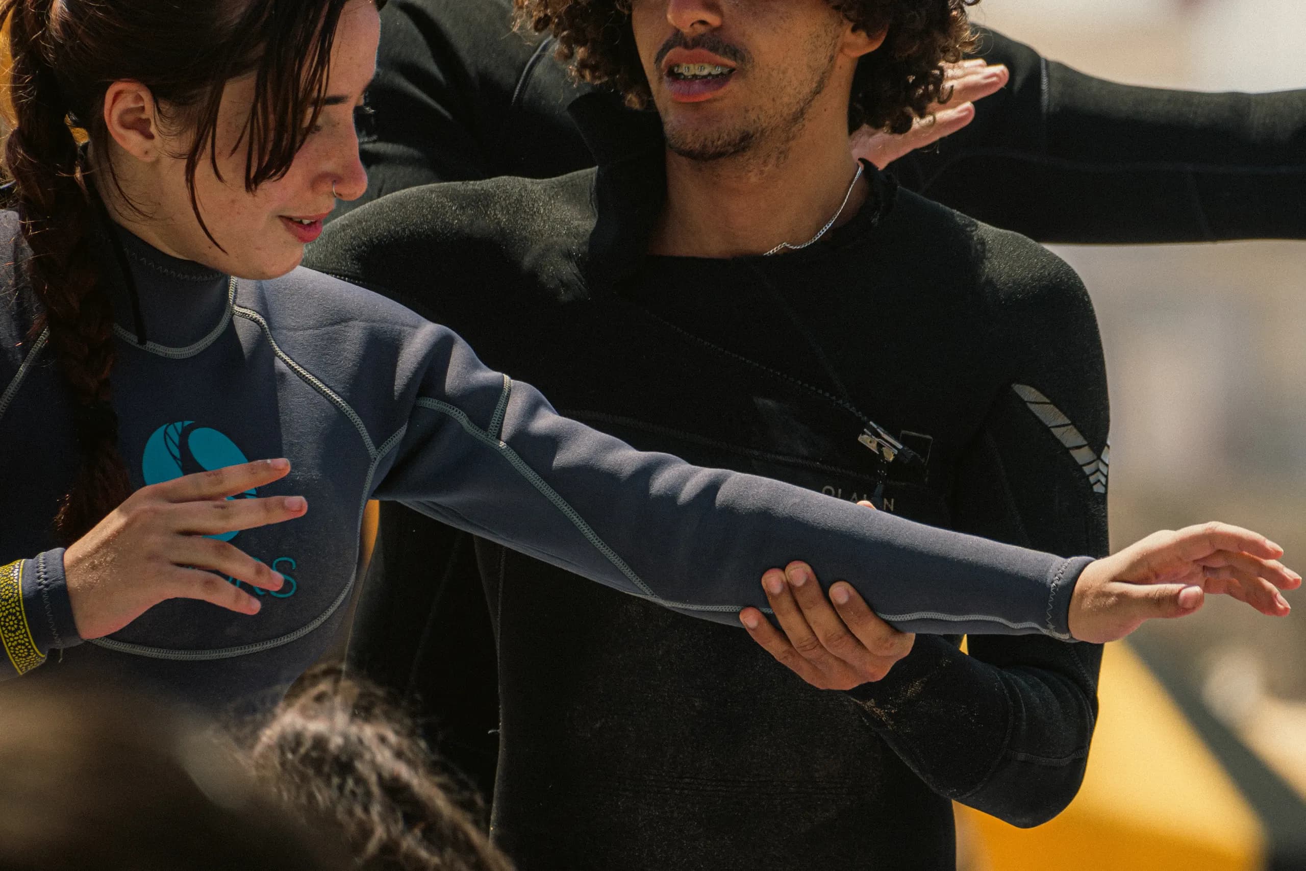 Un instructor local corrige la postura de los brazos de una alumna durante la clase de surf